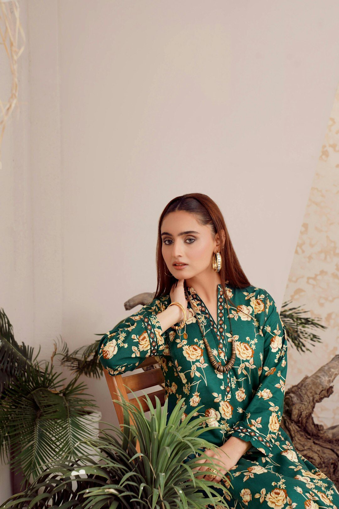 Model wearing a silk emerald blouse and gold accessories